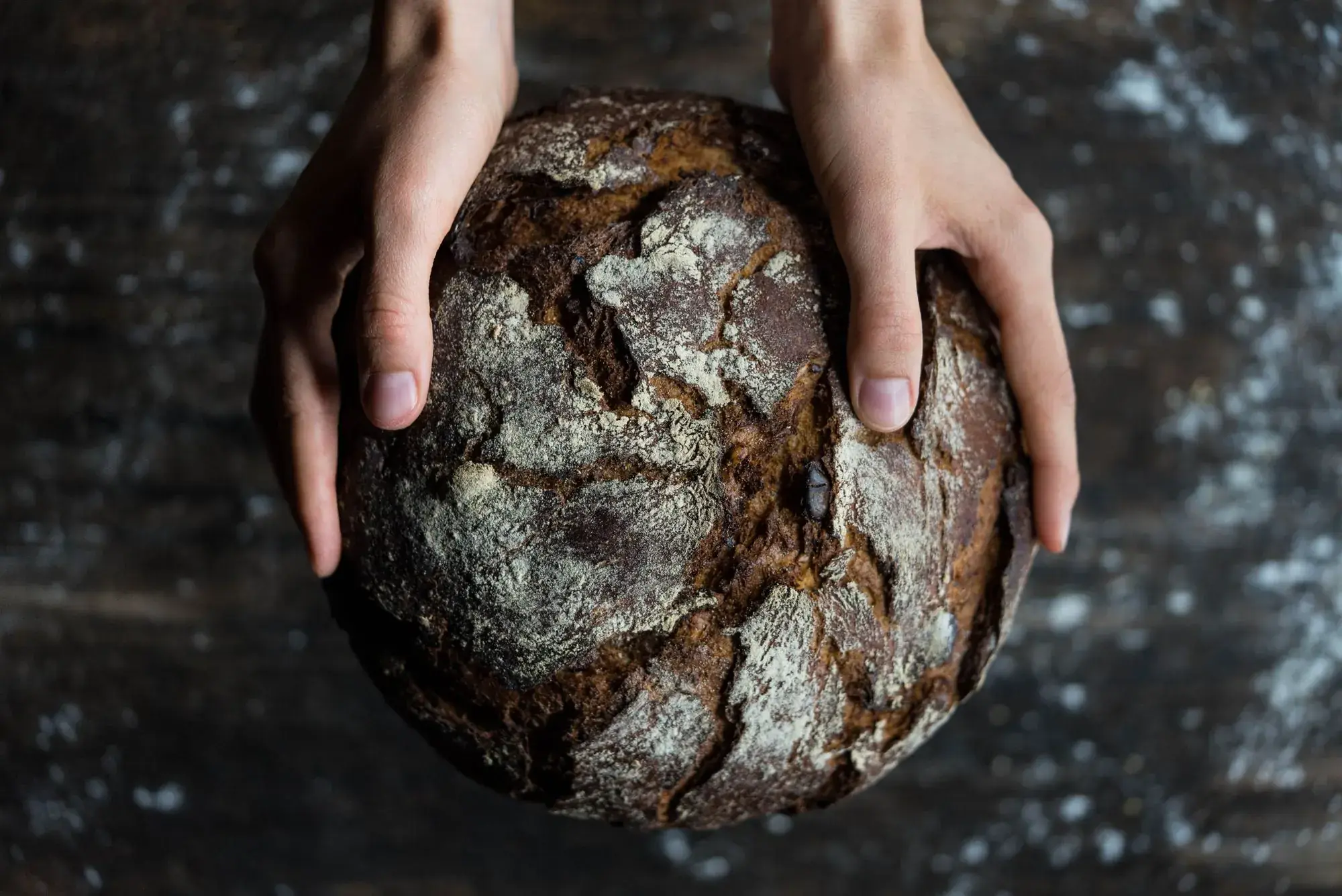 A dark-crusted round loaf held in two hands