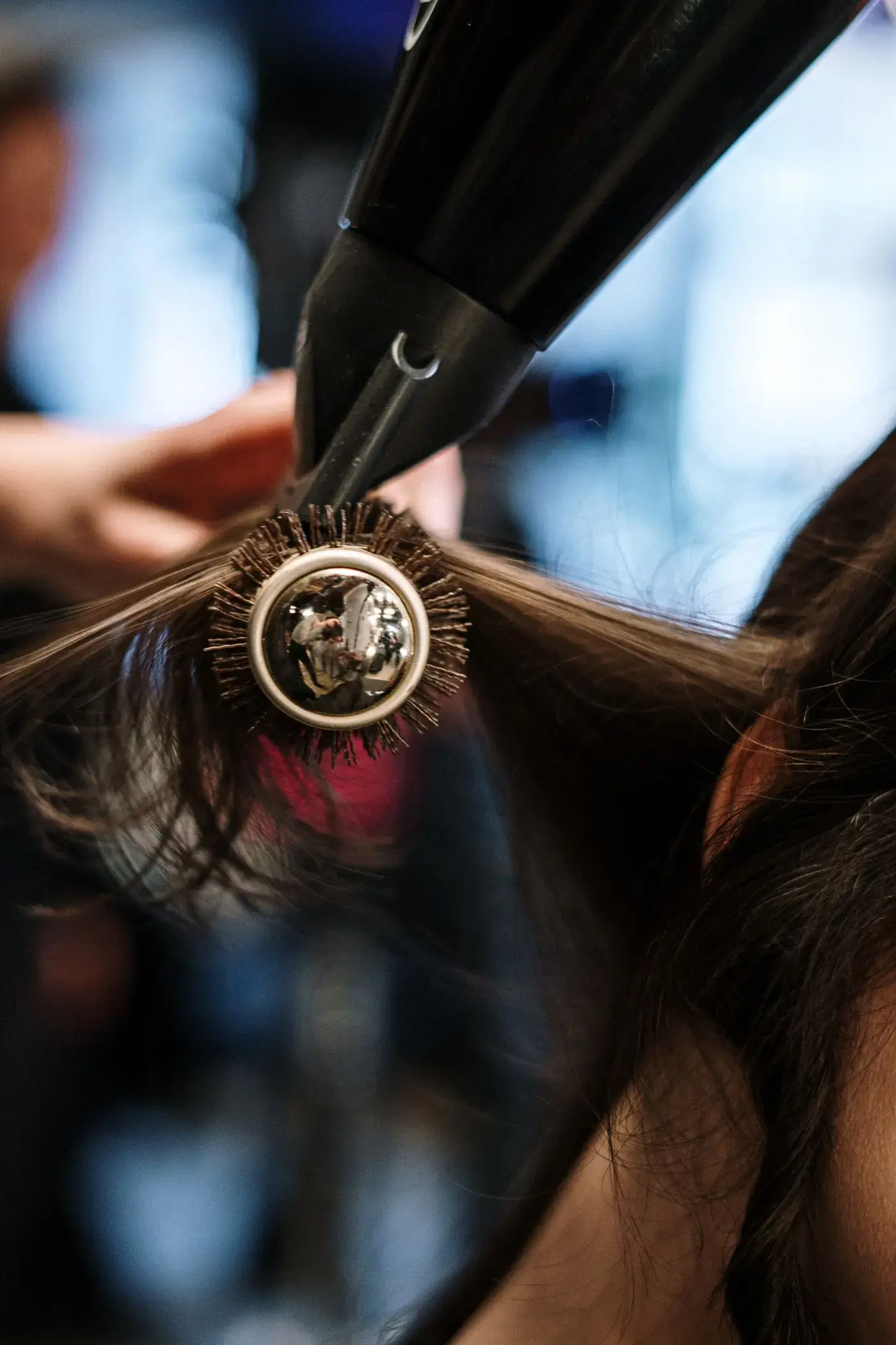 A stylist finishing a blow-dry with a round brush