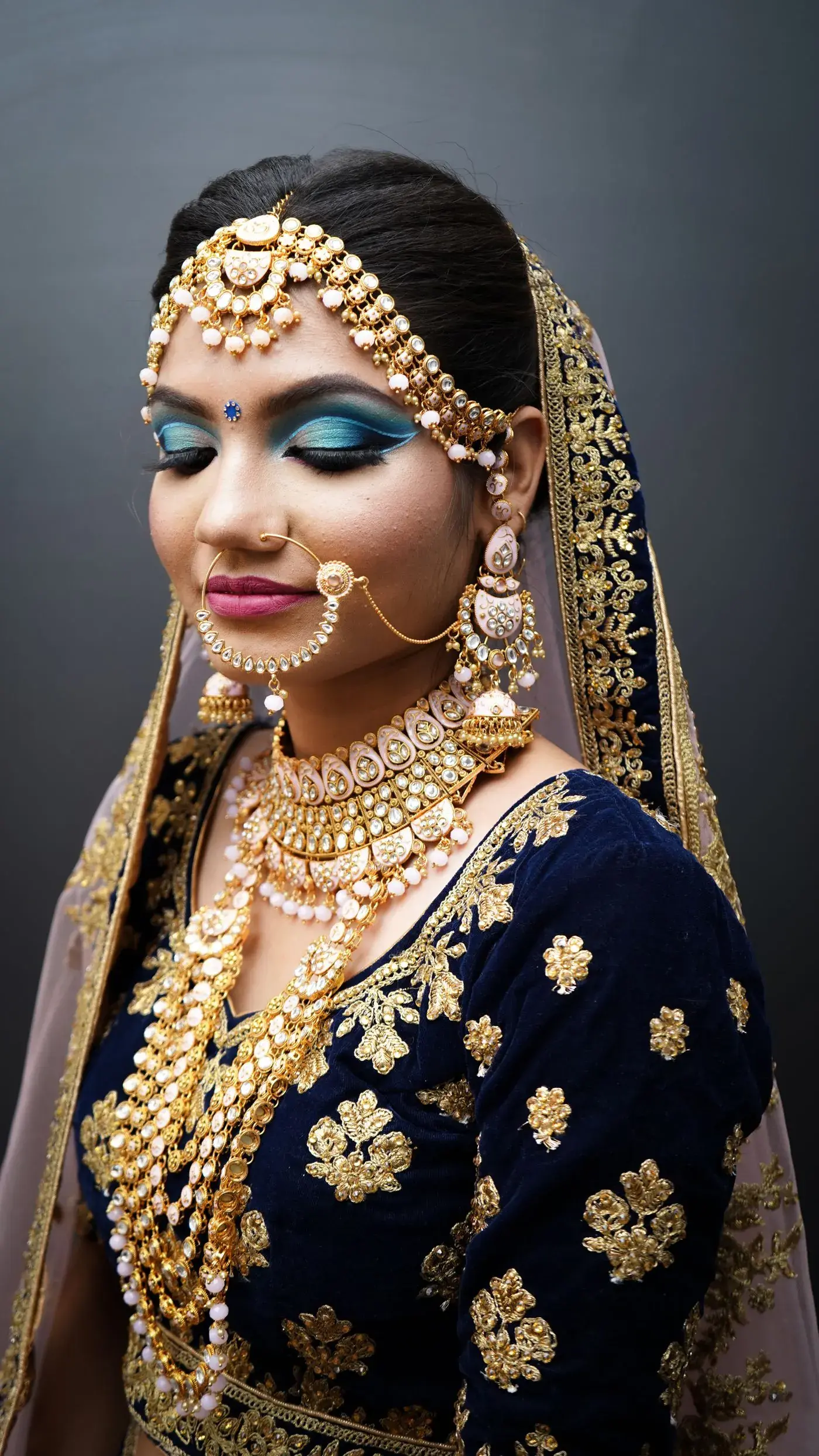 A bride in gold jewellery and a navy lehenga